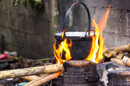Close up of cooking in cauldron licked by flames on open fire fireplace made of bricks stones in field conditions over blurred nature background, horizontal pictureの写真素材