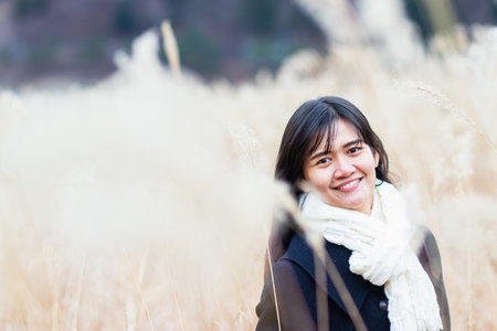 Asian woman smiling and feeling happy on blurred background of reed glass in winter, Japan.の写真素材