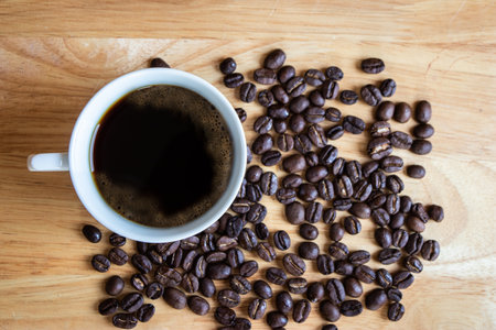 Black coffee placed on a wooden table with coffee beans.の写真素材