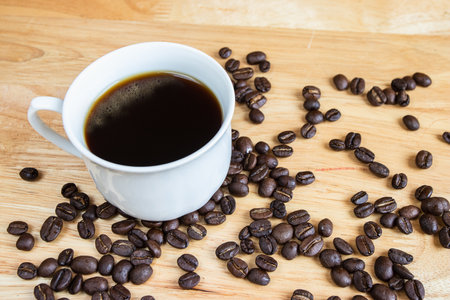 Black coffee placed on a wooden table with coffee beans.の写真素材