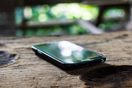 black cellphone on old wood table take photo focus blur.の写真素材
