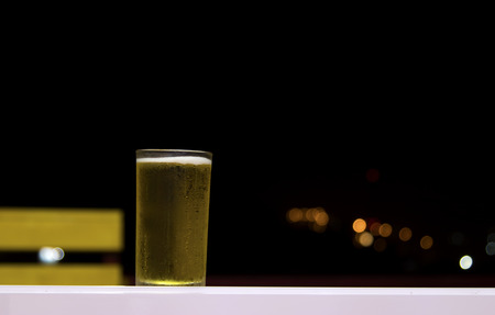 Glass of light beer on a dark pub.の写真素材