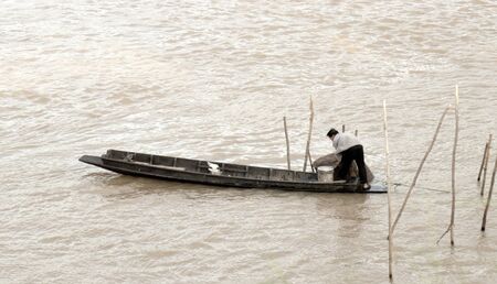 Old fisherman on the boat in lake.