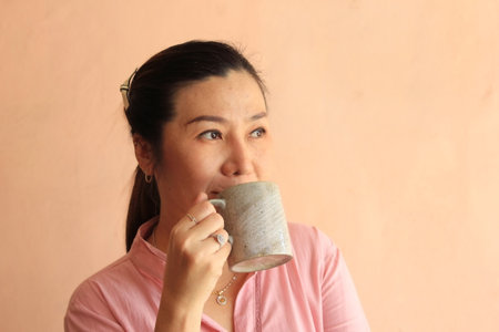 Asian woman drinking a cup of coffee or tea in the morning.の写真素材