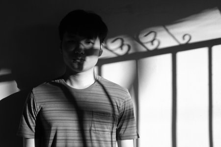 Portrait of young Asian man with shadow on wall. Black and white.の写真素材
