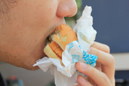 Close up of man eating hamburger with crumpled paper.の写真素材