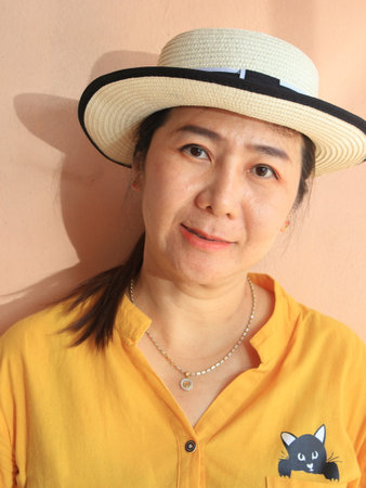 Portrait of Asian woman wearing yellow shirt and straw hat, Thailand.の写真素材