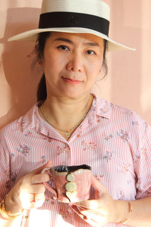 Asian woman wearing hat drinking coffee in the morning, closeup portraitの写真素材