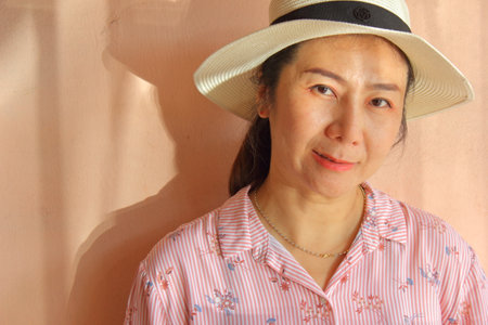 Portrait of asian woman in pink shirt and white hat.の写真素材