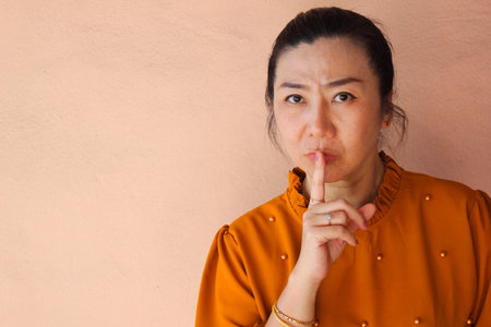 Asian woman with finger on lips asking for silence, secret or secret conceptの写真素材