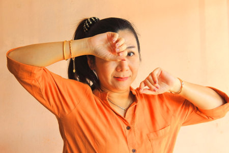 Portrait of thai adult beautiful girl orange shirt relax and smileの写真素材