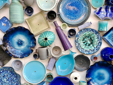 Flat lay of handmade blue ceramic plates and pottery tableware. Artisan craft background for sustainable lifestyle branding.Top view of rustic earthenware dishes and turquoise clay