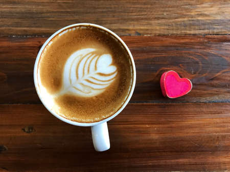 Heart Latte art Coffee in white cup and Red Heart on the wooden table, It's always coffee times.の写真素材