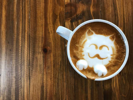 Cute cat face latte art coffee in white cup on wooden table ; love coffee, Cute Neko latte art coffeeの写真素材