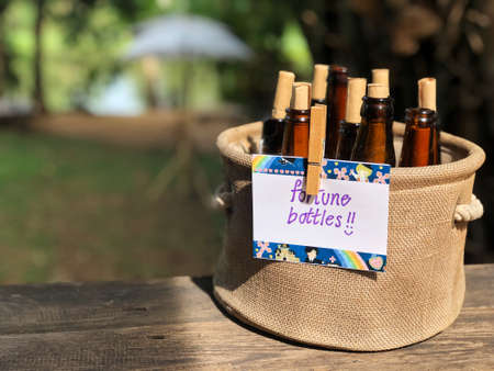 The brown bottles closes the bottle with a cork in a basket made of brown fabric placed on a wooden table in the backyard. And there is a paper written "fortune bottles" with natural  lightの写真素材