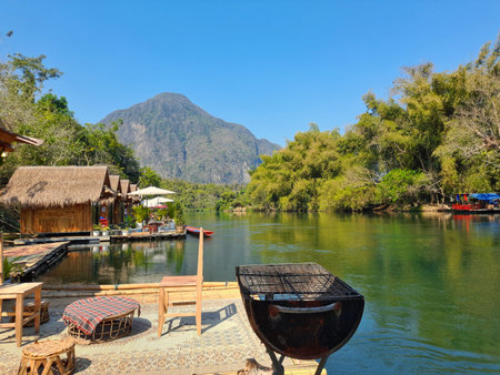 Lao traditional style wooden house on the river with mountain background. Muang Fuang.の写真素材