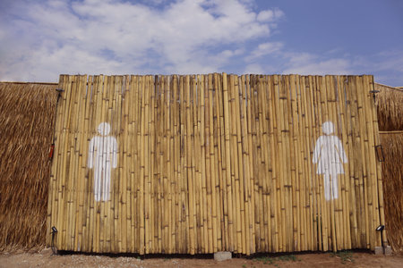 Background design of bamboo fence with white WC restroom painting symbols man and woman. Sign icon male and female toilet.の写真素材