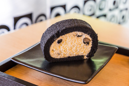 Bamboo charcoal roll cake with fresh cream and black soy beanの写真素材
