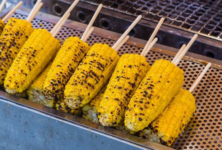 grilled butter corn with stick on grill tableの写真素材