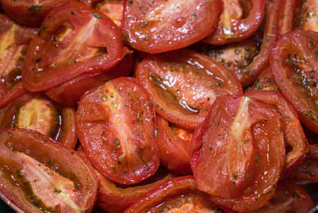 Roasted tomatoes with herbs, on a baking tray.の写真素材