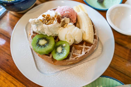 Waffles with vanilla and strawberry ice cream with fresh fruit kiwi and banana.の写真素材