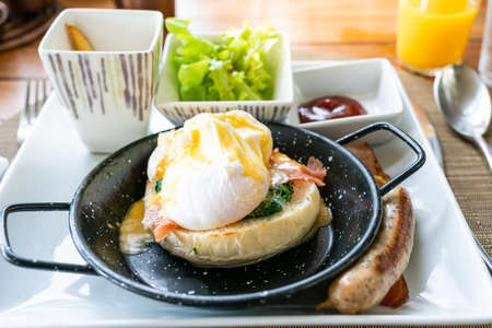 Close up egg benedict with bacon and sausage - delicious american breakfast