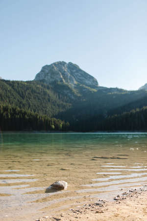 Nice view of the mountain lake, forest and mountains. The lake and the shore are in focus.の写真素材