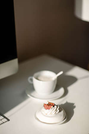 Home interior. Work desk with a computer, a cup of coffee and a sweet dessert.の写真素材
