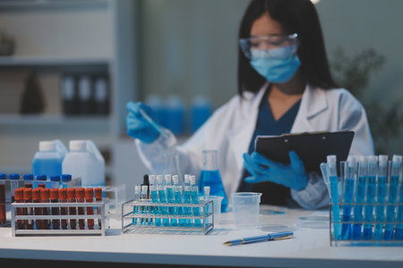 Group of dedicated scientist conduct chemical experiment in medical laboratory, carefully drop precise amount of liquid from pipette into test tube for vaccine drug or antibiotic development. Neotericの写真素材