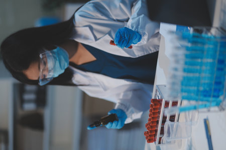 Group of dedicated scientist conduct chemical experiment in medical laboratory, carefully drop precise amount of liquid from pipette into test tube for vaccine drug or antibiotic development.の写真素材