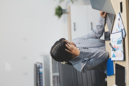 Asian women are stressed while working on laptop, Tired asian businesswoman with headache at office, feeling sick at work, copy spaceの写真素材