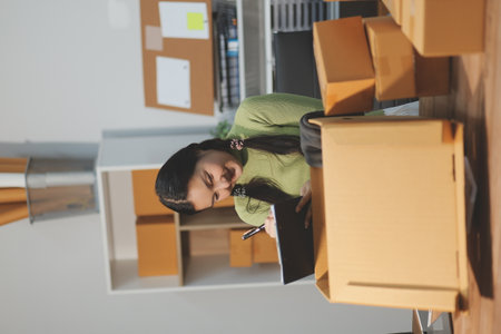 Startup SME small business entrepreneur of freelance Asian woman wearing apron using laptop and box...