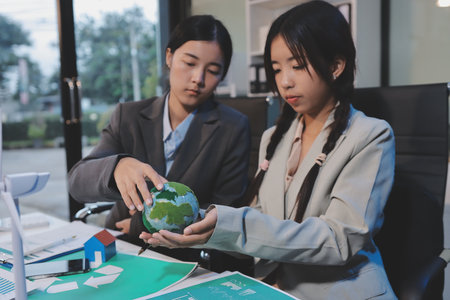 Asian woman lead young group of multiethnic businesspeople in team meeting, using laptop computer for ESG topic presentation on monitor. Sustainable business practice, people work at home conceptの写真素材