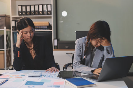 Asian women are stressed while working on laptop, Tired asian businesswoman with headache at office, feeling sick at work, copy spaceの写真素材