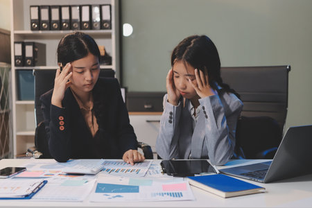 Asian women are stressed while working on laptop, Tired asian businesswoman with headache at office, feeling sick at work, copy spaceの写真素材