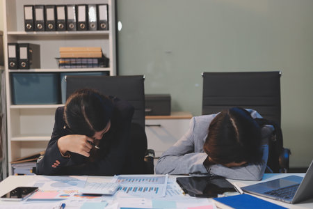 Asian women are stressed while working on laptop, Tired asian businesswoman with headache at office, feeling sick at work, copy spaceの写真素材