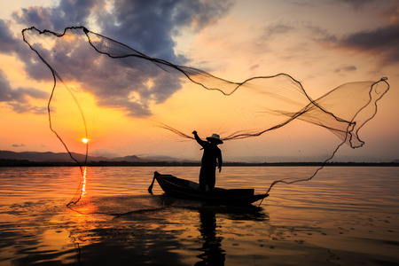 Silhouetted of a fisherman in the morning on the lakeの写真素材