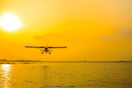 Low-flying aircraft above the lake with sun burst flare