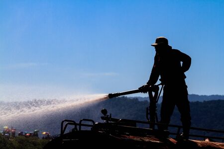 Silhouette of fireman spay a water during firefighting training exercise
