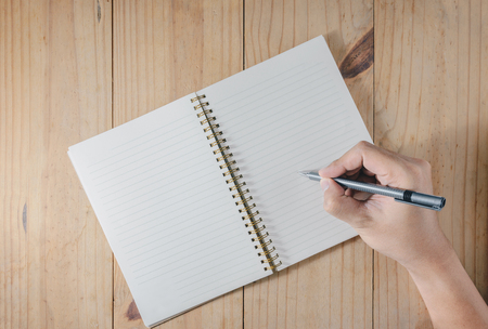 Hand of man use pencil writing on white notebook on wooden tableの写真素材