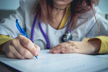 Close up of female doctor filling patient medical historyの写真素材