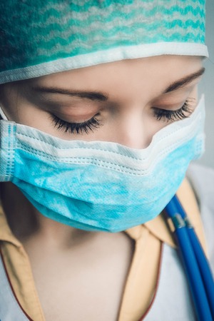 Portrait of looking down female doctor wearing protective mask and hatの写真素材