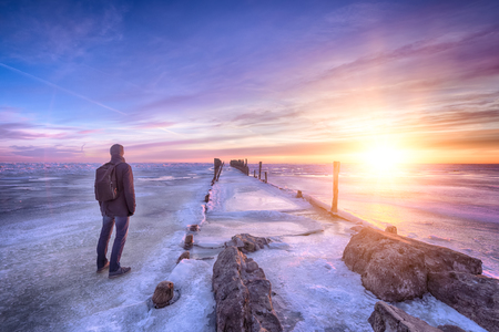 Winter seascape of wood breakwaters and traveller on frozen Baltic seaの写真素材