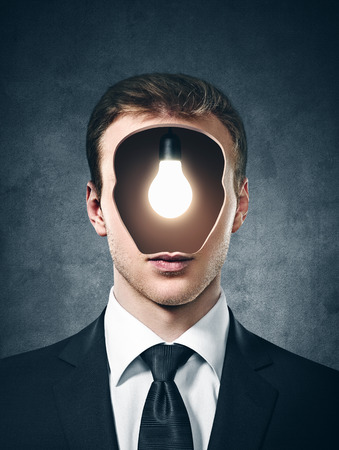 businessman with lamp inside his head on the gray backgroundの写真素材