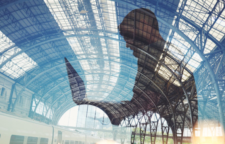 Double exposure of man with lap top on the train station
