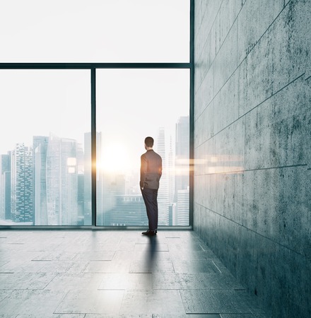 Business man in suit looking at sunrise in the city.の写真素材