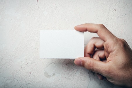 Hand holding business card on wall backgroundの写真素材