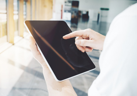 A man holding a tablet in his hand  and touching a screen