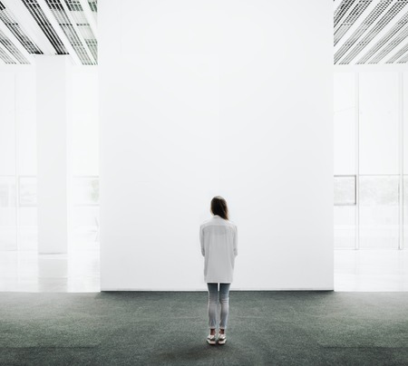 Young woman walking through on the exhibition hall and examines the gallery