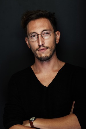 Portrait of handsome young man wearing glasses and watch. Man standing on the black background and...